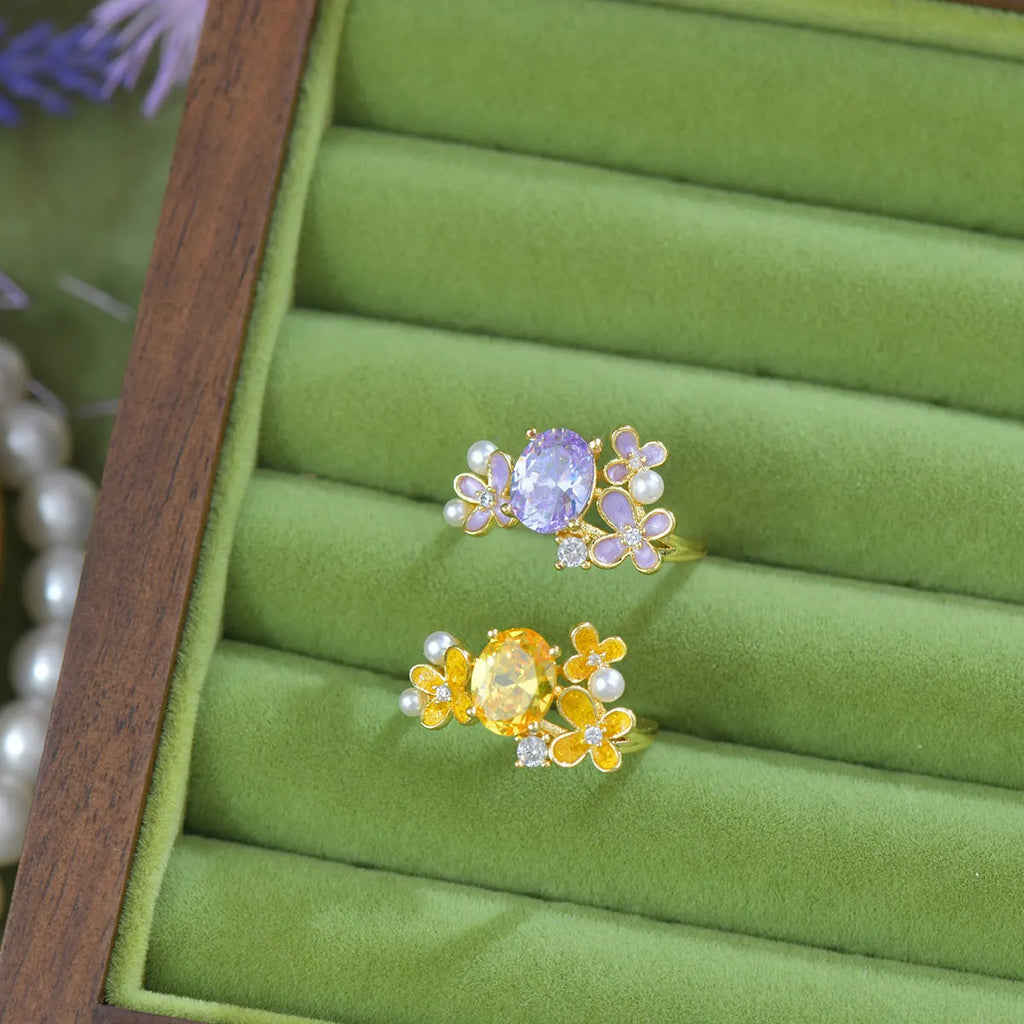 Yellow women's open ring with a flower shape and zircon detailing on a white background.