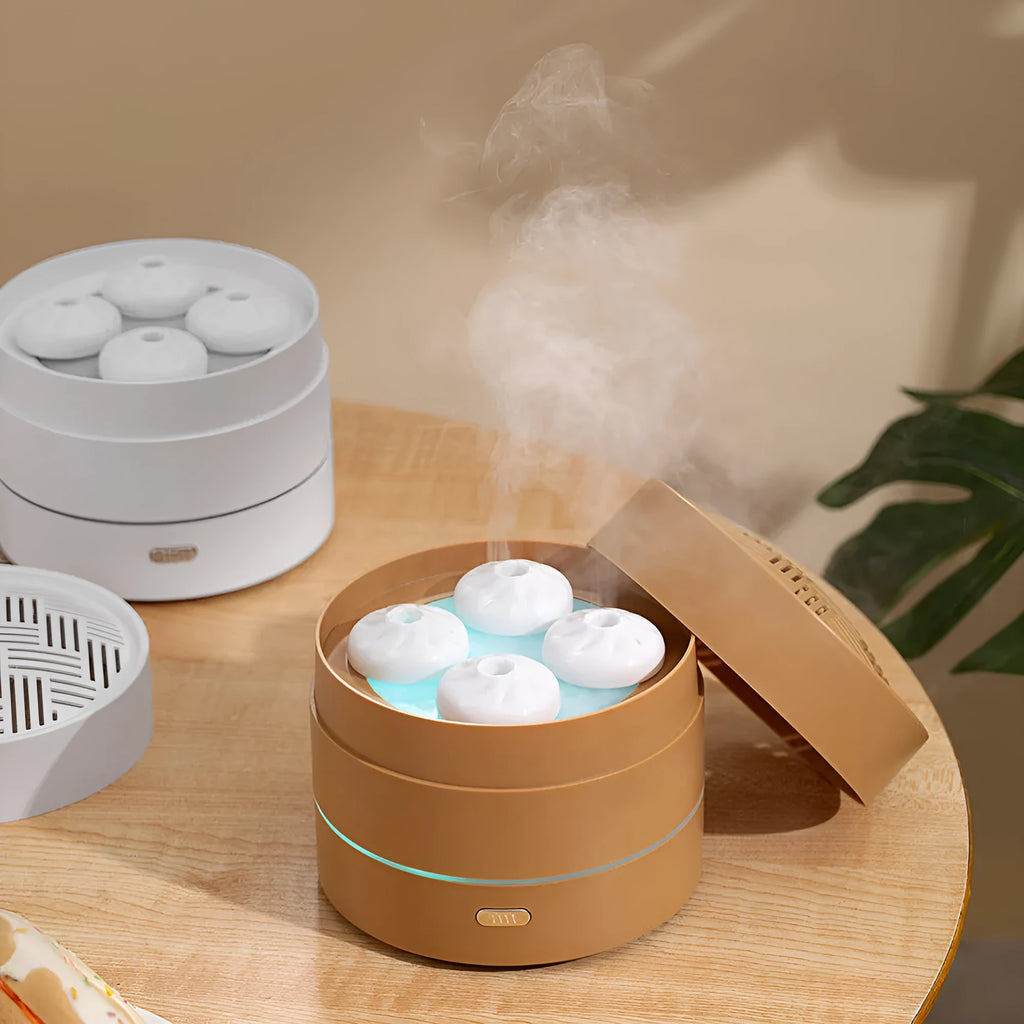 White ultrasonic aroma diffuser with four steam nozzles and LED light on a wooden table