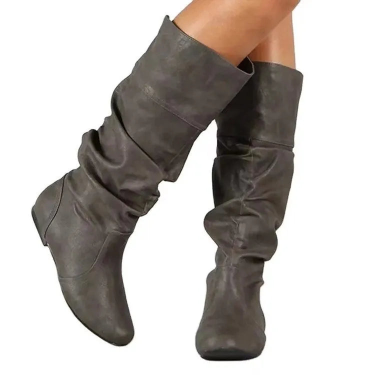 Women's black flat slip-on boots with round toe and high shaft on a white background.