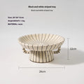 Black and white striped synthetic resin fruit plate on a plain surface.