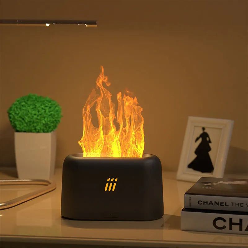 Black round flame aroma diffuser humidifier with LED lights and remote control on a table.