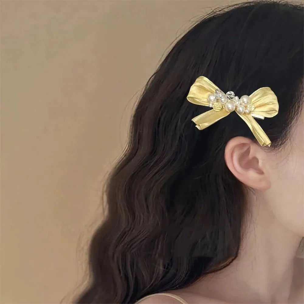 Yellow cloth bow barrette with rhinestone and pearl accents on duckbill hair clip