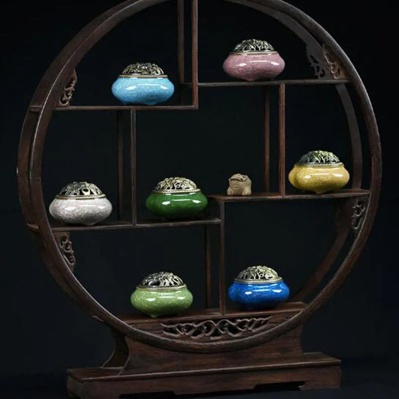 Ceramic incense burner with retro packaging in various colours on wooden surface.