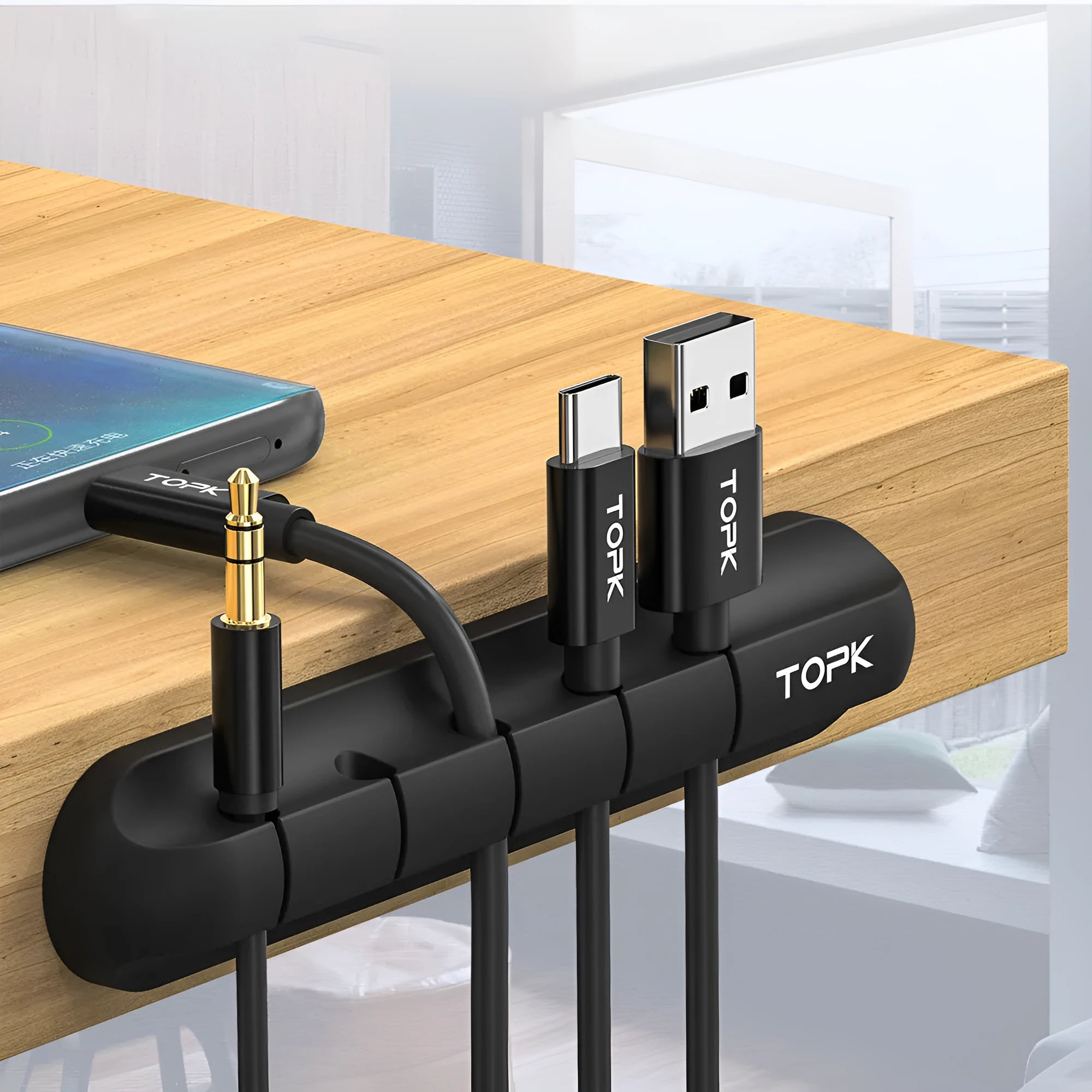 Black organic silicone desktop cable manager clips holding USB cables on a desk