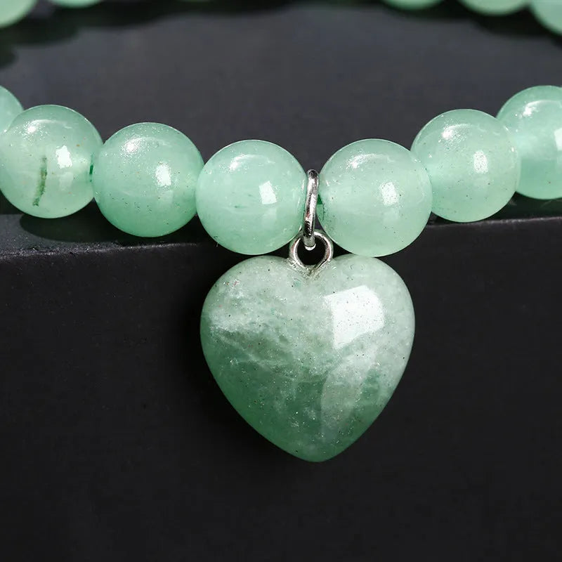 Natural stone love heart pendant bracelet on wrist, showing Tigereye, crystal or aventurine beads.
