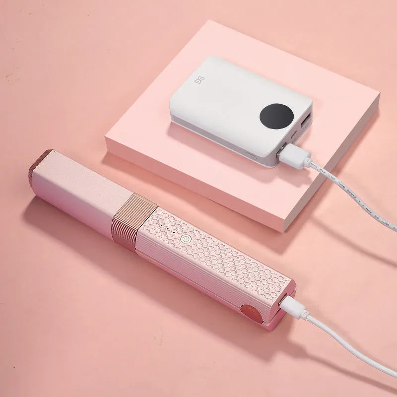 Compact pink cordless USB hair straightener and curler with ceramic plates on a white background.