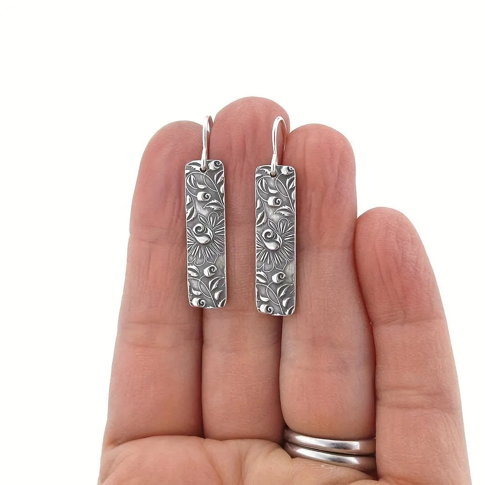 Silver-coloured long geometric drop earrings with carved vine patterns
