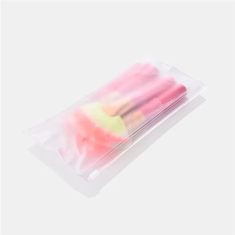 Pink cosmetic makeup brush set with wooden handles and synthetic bristles laid out on a surface