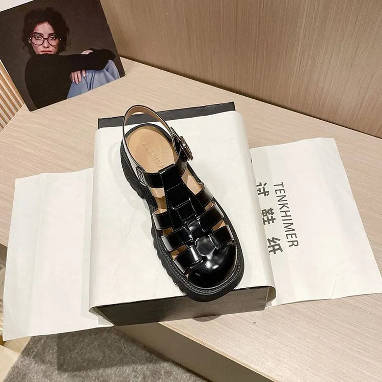 Women's black retro platform sandals with closed toe, hollow out holes, and a silver buckle closure on a chunky rubber heel.