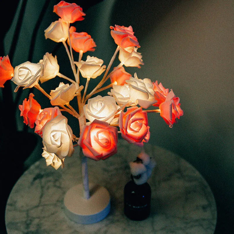 White and red rose flower LED table lamp with bonsai tree and garland lights on a table.