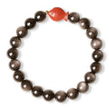 Natural obsidian bracelet with round beads and red cinnabar fungus decoration on wrist