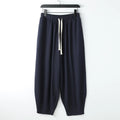 Loose fit linen harem pants with tapered legs and ankle ties on a mannequin, showing elasticated waist.