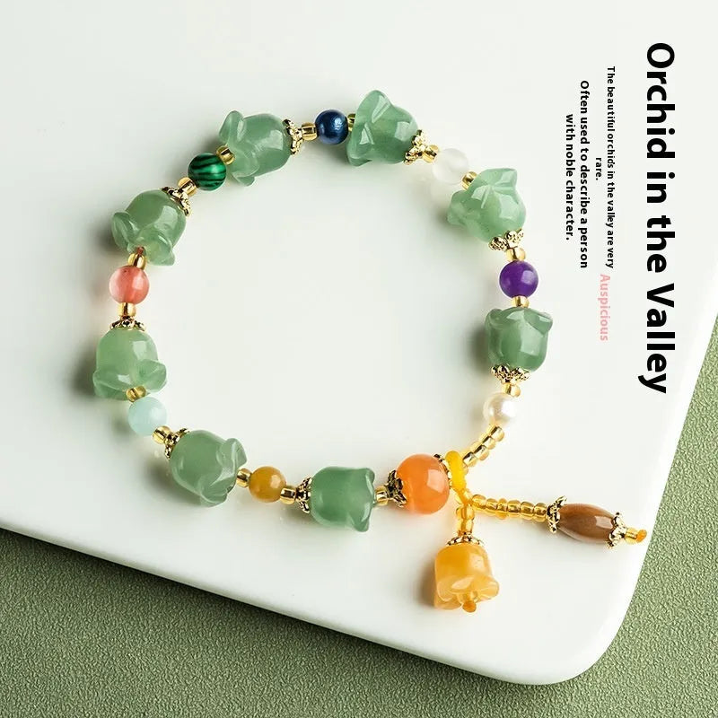 Close-up of a women's jade bracelet with hand-carved orchid-shaped beads on a wrist.