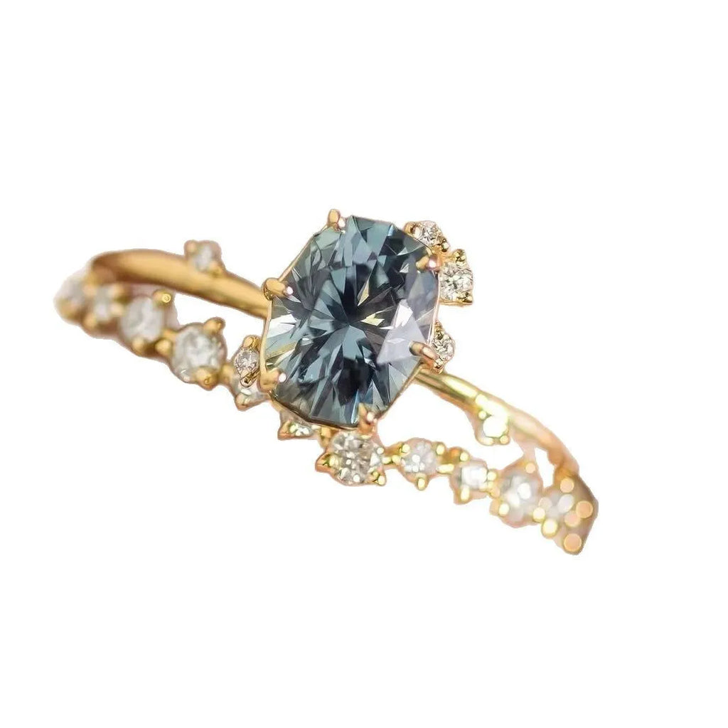 Close-up of a gold-plated floral ring with a central green zircon stone on a model's hand.