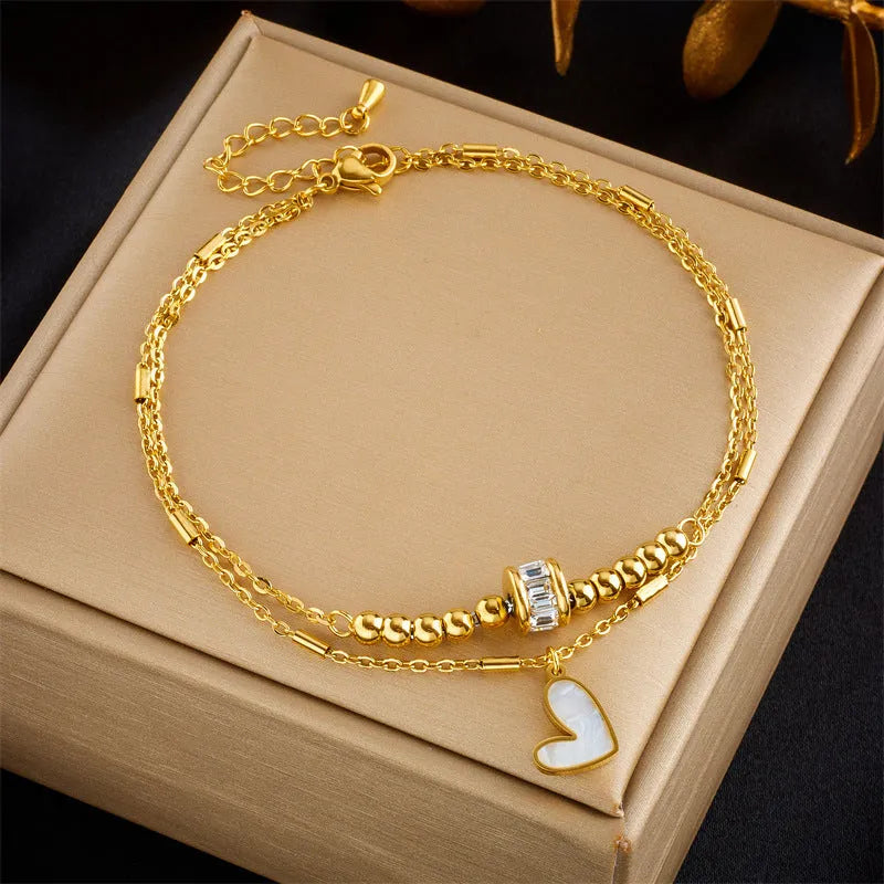 Gold titanium steel double-layer ankle chain with love heart charm and tassel on a white background