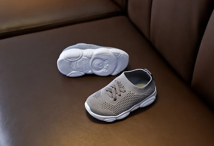 Children's white fabric lazy shoe with a non-slip rubber sole, shown on a foot.