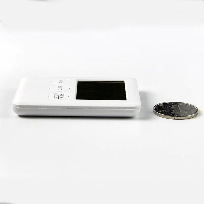 Black and white digital kitchen timer with magnetic strip on back and LCD display.