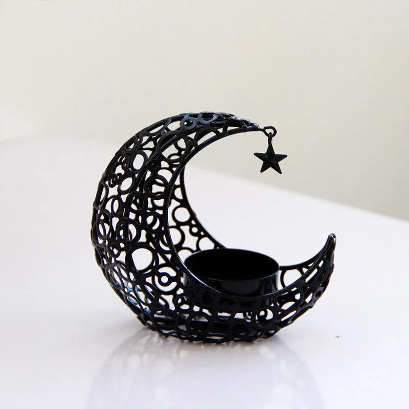 Black metal crescent moon candle holder with star cutouts on a table