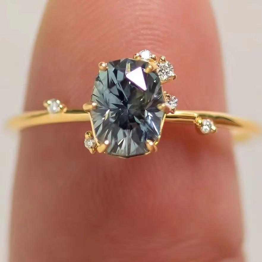 Close-up of a gold-plated floral ring with a central green zircon stone on a model's hand.