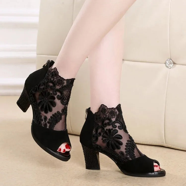 Black lace gladiator sandals with a square high heel, zip closure, and peep toe on a woman's foot