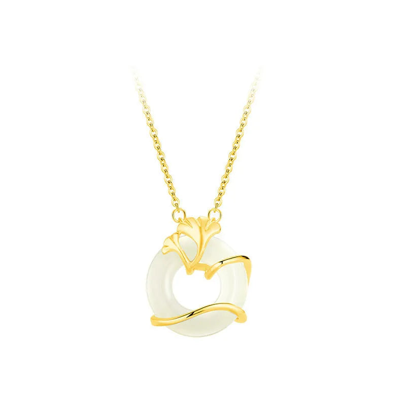 Close-up of a sterling silver peace buckle necklace with a cross chain and ginkgo details, shown in a gold tone.