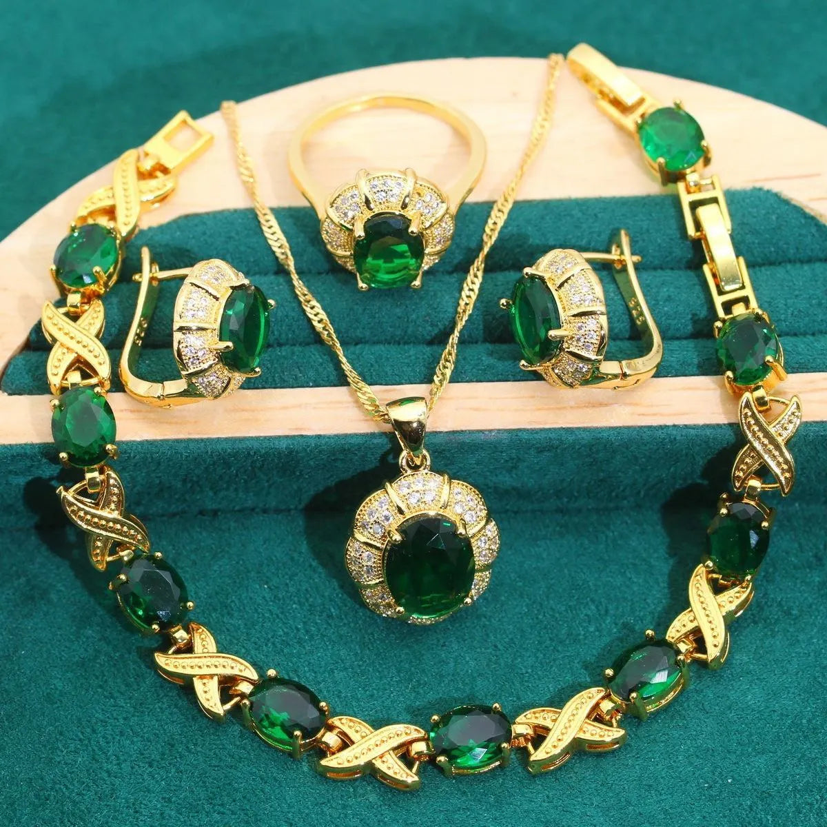 Gold-coloured jewellery set with sparkling blue cubic zirconia stones, showing necklace, earrings, ring, and bracelet.