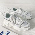 Men's white platform dad shoes with lace-up front and mesh lining on a neutral background.