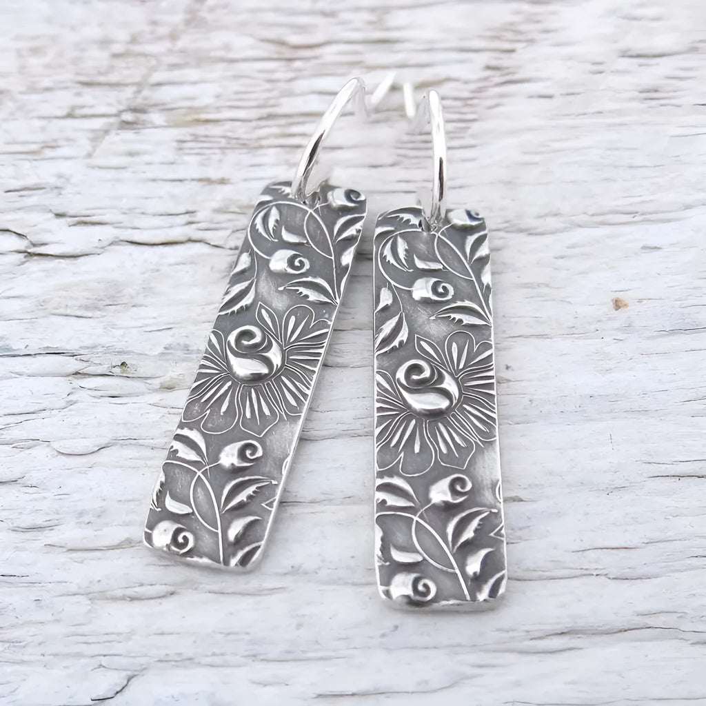 Silver-coloured long geometric drop earrings with carved vine patterns