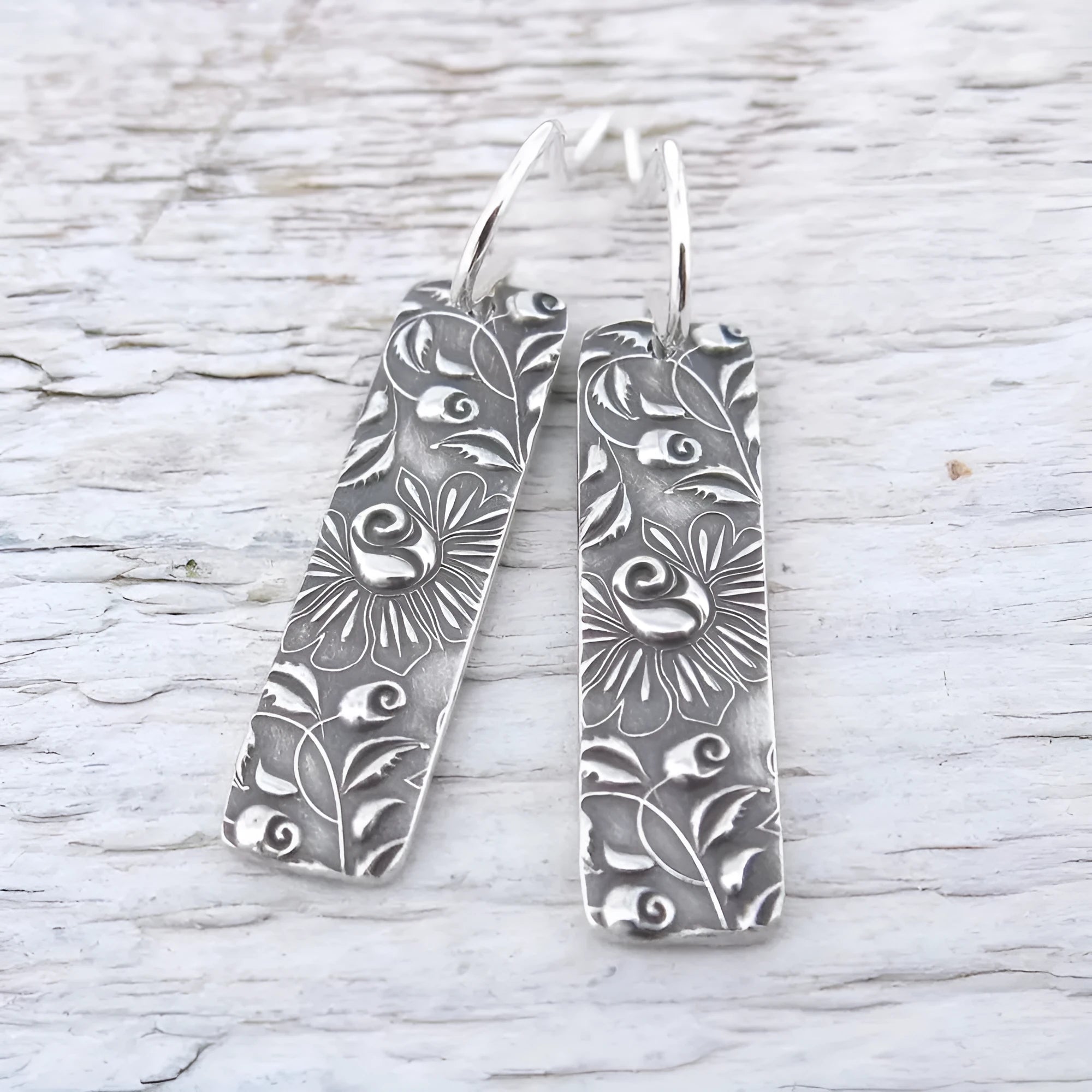 Silver-coloured long geometric drop earrings with carved vine patterns