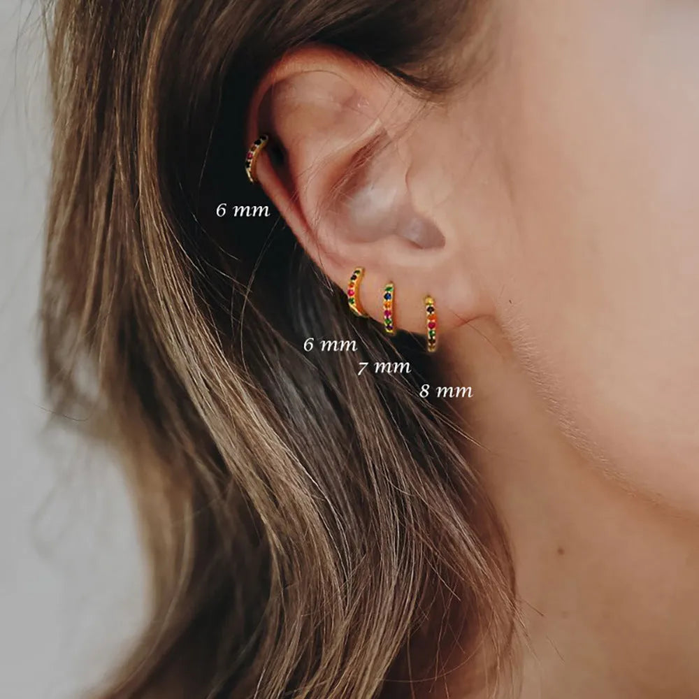 Perforated geometric circle stud earrings with zircon detail in gold, rose gold, and silver tones.