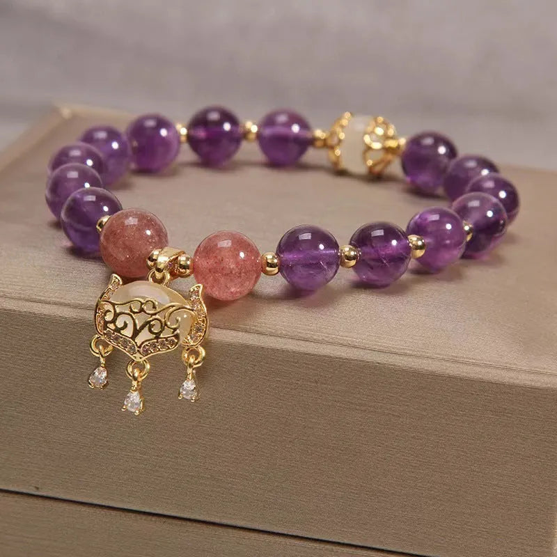 Close-up of a handmade copper bracelet for women with a drop-shaped longevity lock charm, Ruyi element, amethyst stones, and gold accents.