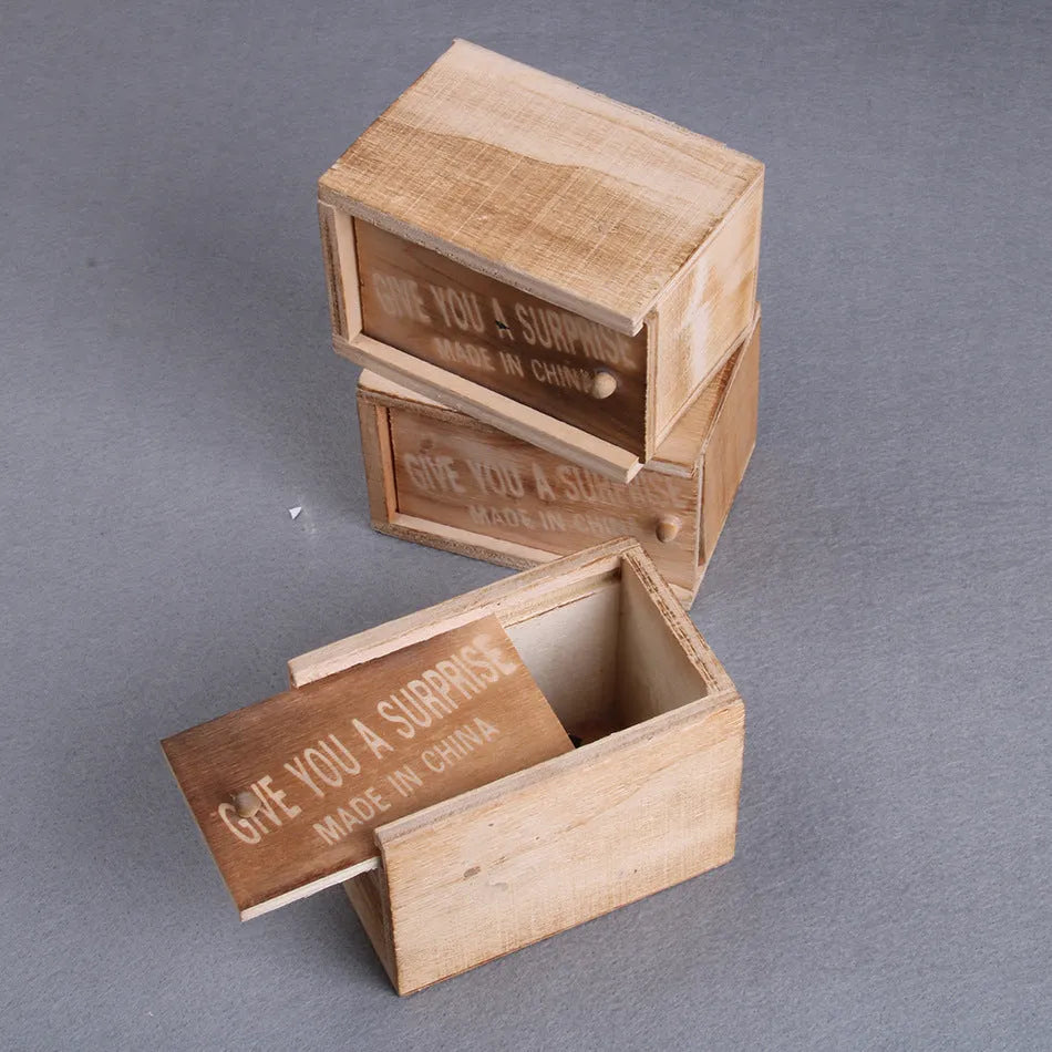 Wooden prank box with lid open showing a lifelike jumping spider inside on a white background.