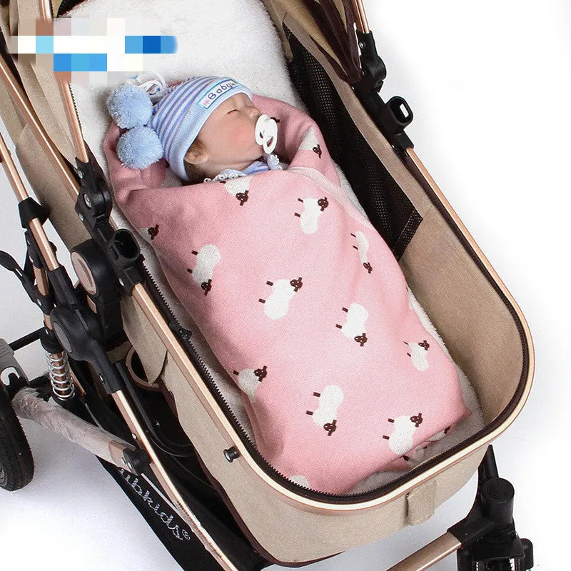 Grey and pink baby sheepskin blanket measuring 100cm by 80cm on a crib