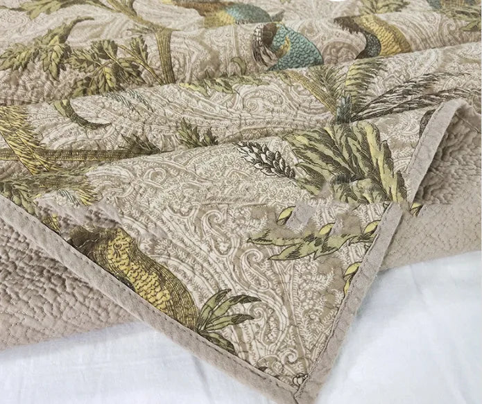 Blue American floral and bird patterned cotton quilted bedspread set on a bed, showing the 230x250 cm size