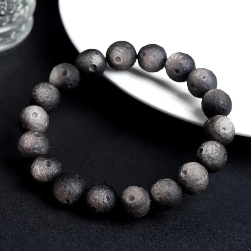 Natural obsidian crater ball bracelet with textured beads in silver stone meteorite finish.