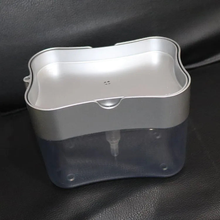 A grey automatic touch-free soap dispenser for the kitchen on a worktop.
