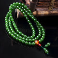 Green quartz rock jade bracelet with 108 beads and a Buddha head pendant on a wrist.