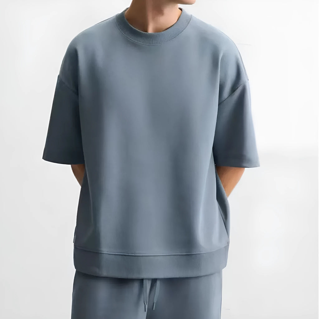 Loose-fitting white short sleeve top and matching shorts set on a hanger, showing round collar and cloth texture.