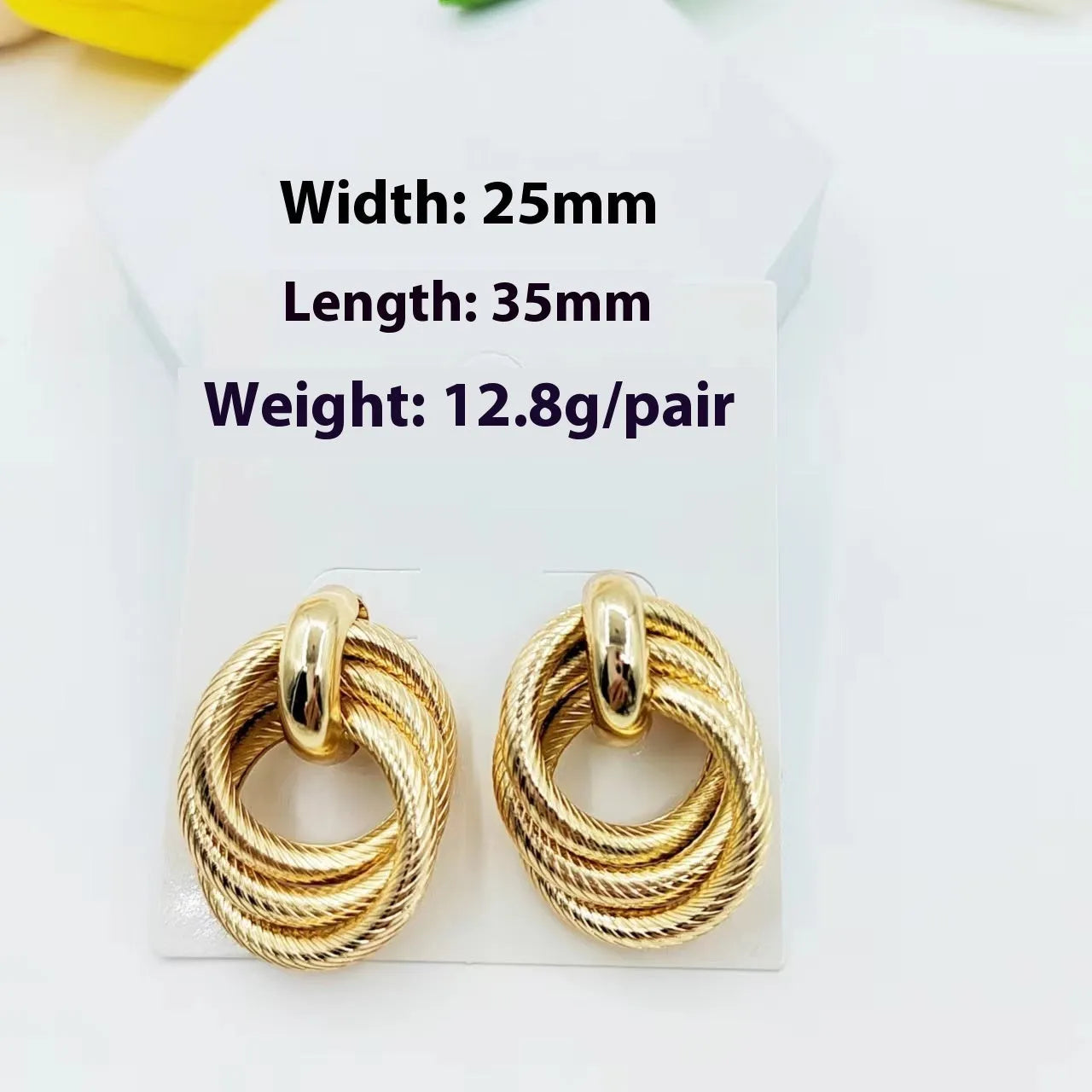 Geometric ring embossed twisted metal stud earrings in gold colour on a plain background