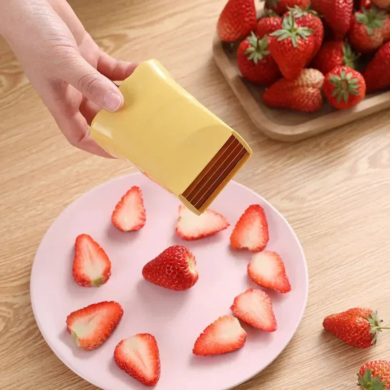 Green stainless steel cup fruit slicer with sliced strawberries on a light background