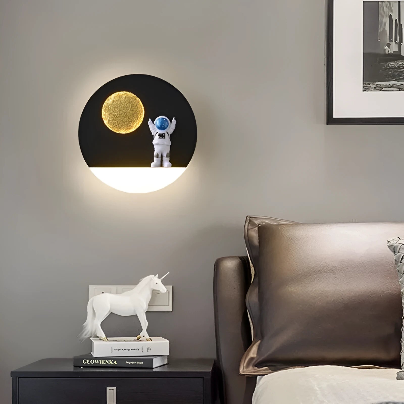 Modern black or white astronaut-shaped wall lamp with integrated shelf and LED light for bedside use.