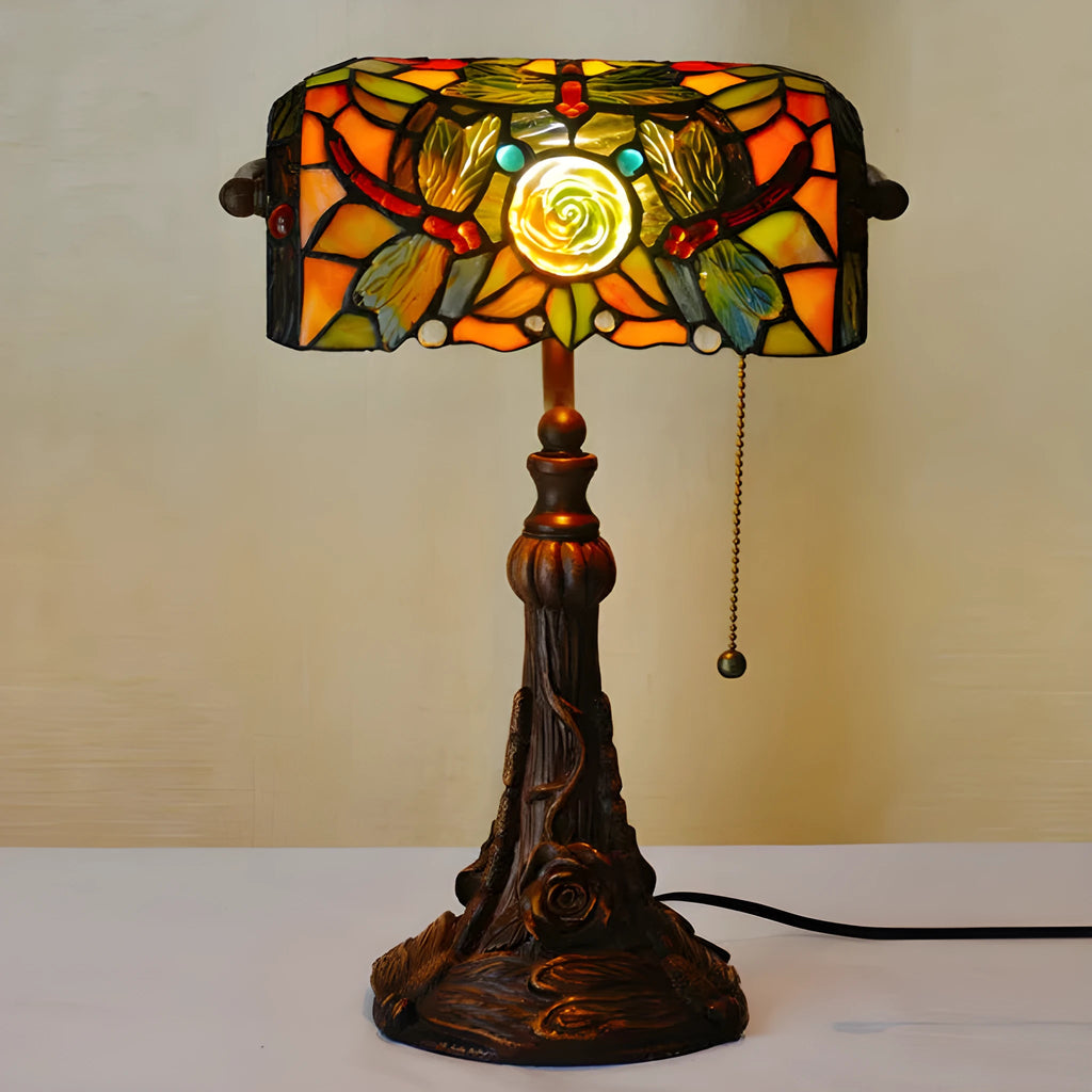 Tiffany stained glass table lamp with coloured lampshade and resin base on a desk