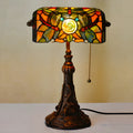 Tiffany stained glass table lamp with coloured lampshade and resin base on a desk