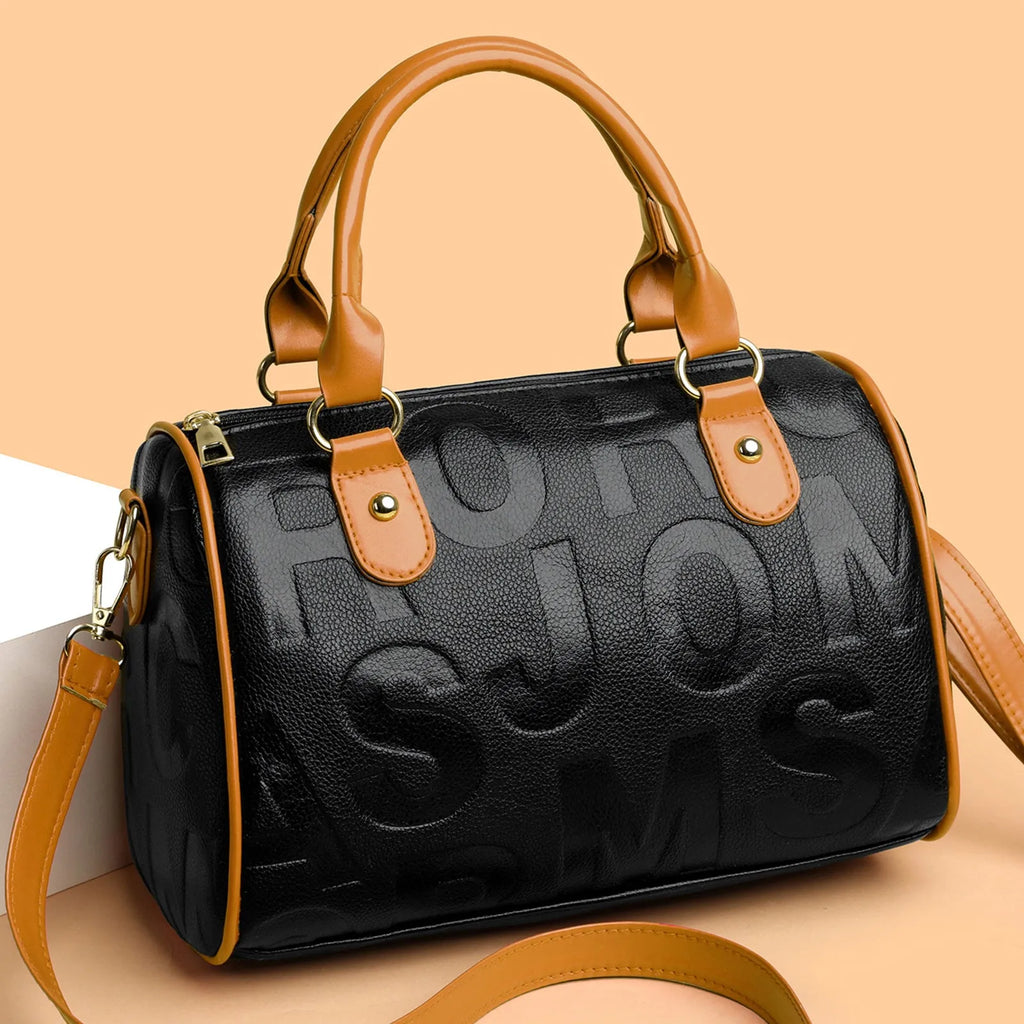 Brown cylindrical leather-effect crossbody bag with three shoulder straps on a table.