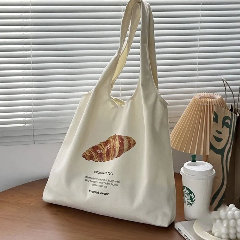Beige canvas tote bag with croissant-shaped shoulder design and wide 44cm structure