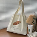 Beige canvas tote bag with croissant-shaped shoulder design and wide 44cm structure