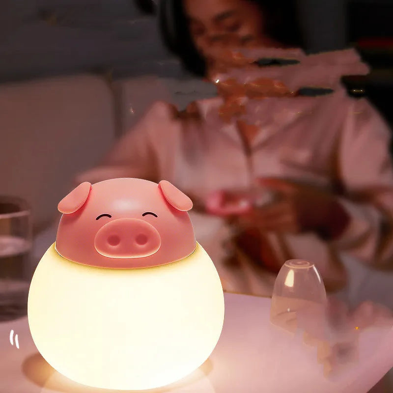Pink pig silicone pat bedside lamp with USB LED light source on a table