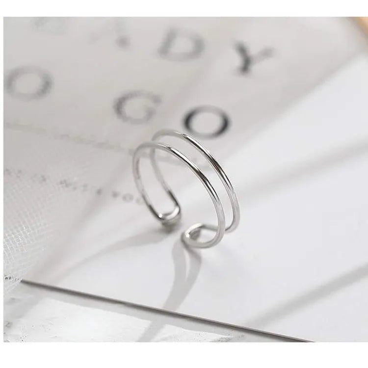 Silver-plated geometric cross ring with an adjustable opening on a copper base.