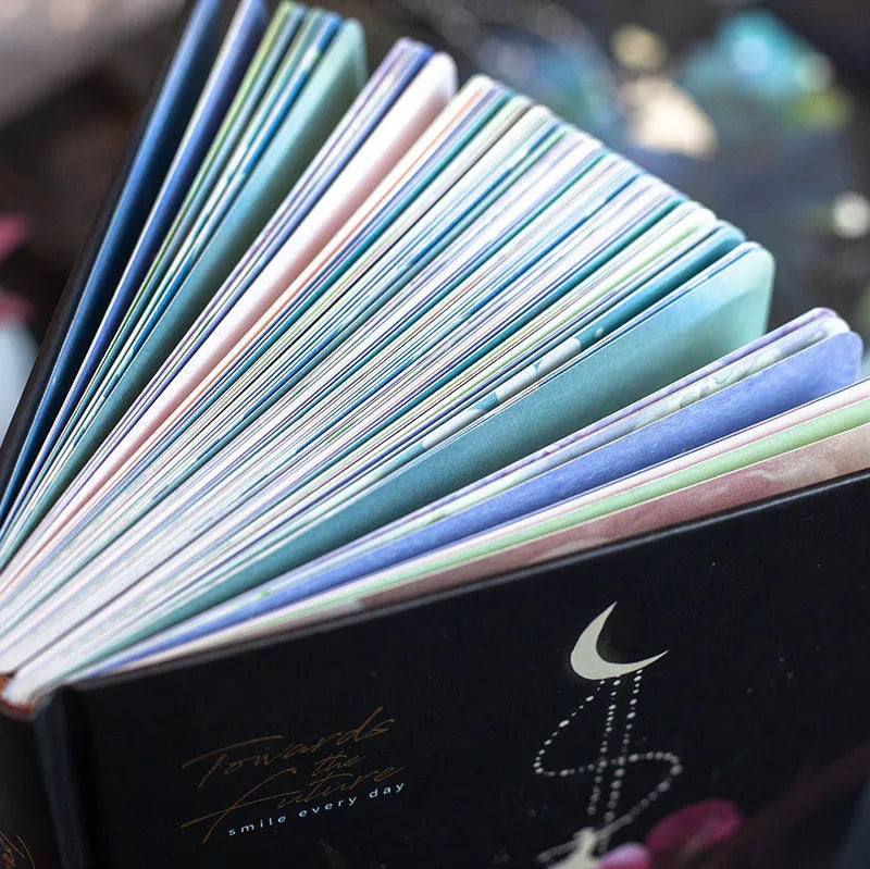 A5 notebook with a luminous cover open to show pages with colour illustrations.