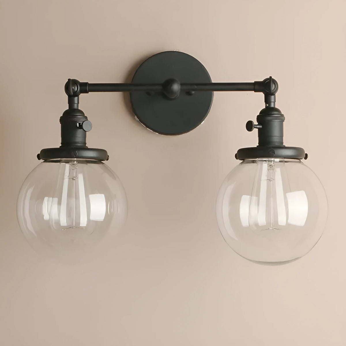 Double headed black iron wall lamp with spherical glass shades on a wall